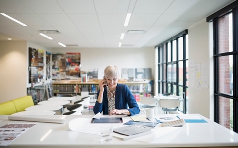 woman sat in a bright and airy office on the phone and reading a document