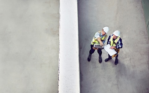 birds eye view of two workers wearing white hard hats and high vis jackets