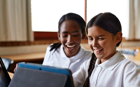 Children smiling reading tablet