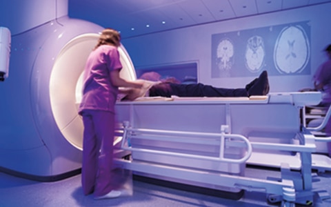 nurse standing to the side of a patient in a MRI scanner