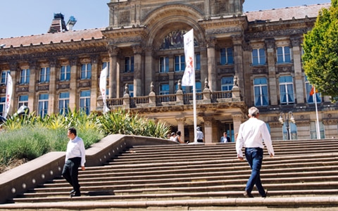 people walking on stairs outside large building